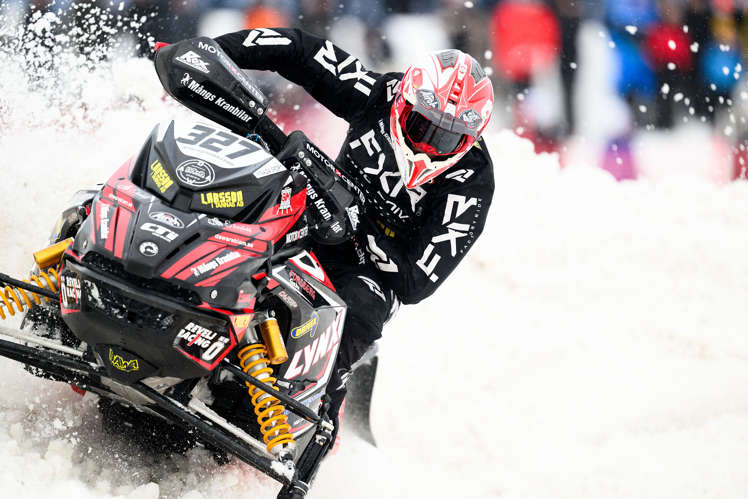 Alfred Gunnarsson tar en kurva med sin skoter så att snön sprutar.