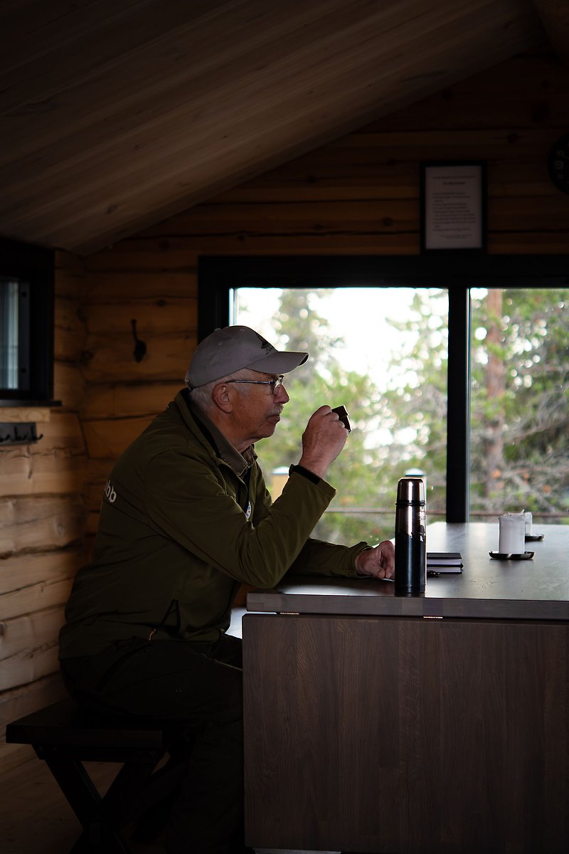 Nils-Erik Yngvesson sitter i Räkaklitts toppstuga och dricker kaffe.